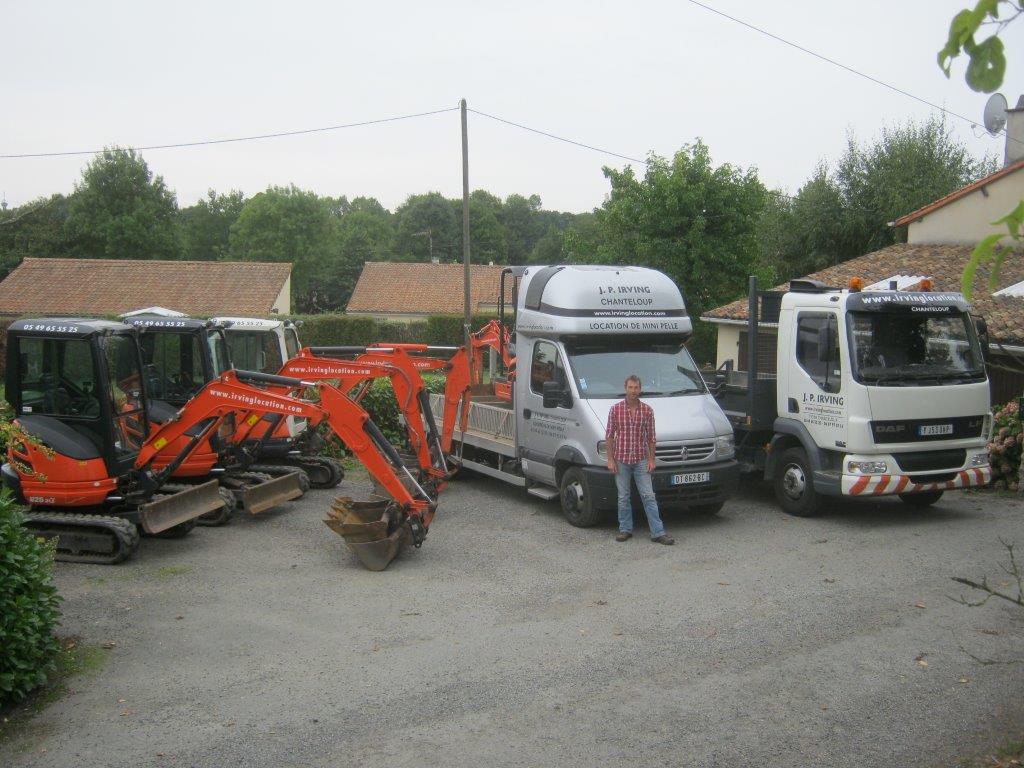 Phil Irving standing in front of mini diggers, trucks, delivery vans and dumper truck