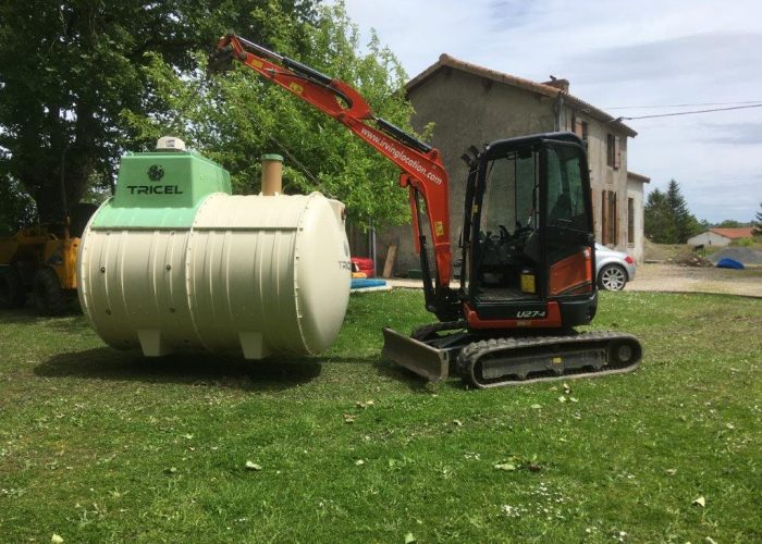 2.7 tonne mini-digger lifting a septic tank in a garden