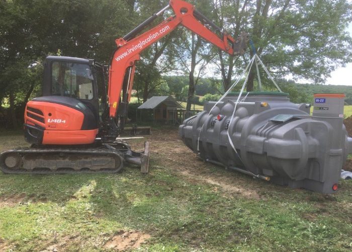 using a mini-pelle to move a fosse-septique tank in a garden