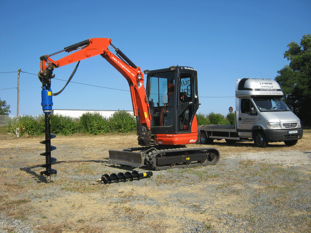 mini digger with post hole borer attached, pointing downwards ready to drill a hole in the ground