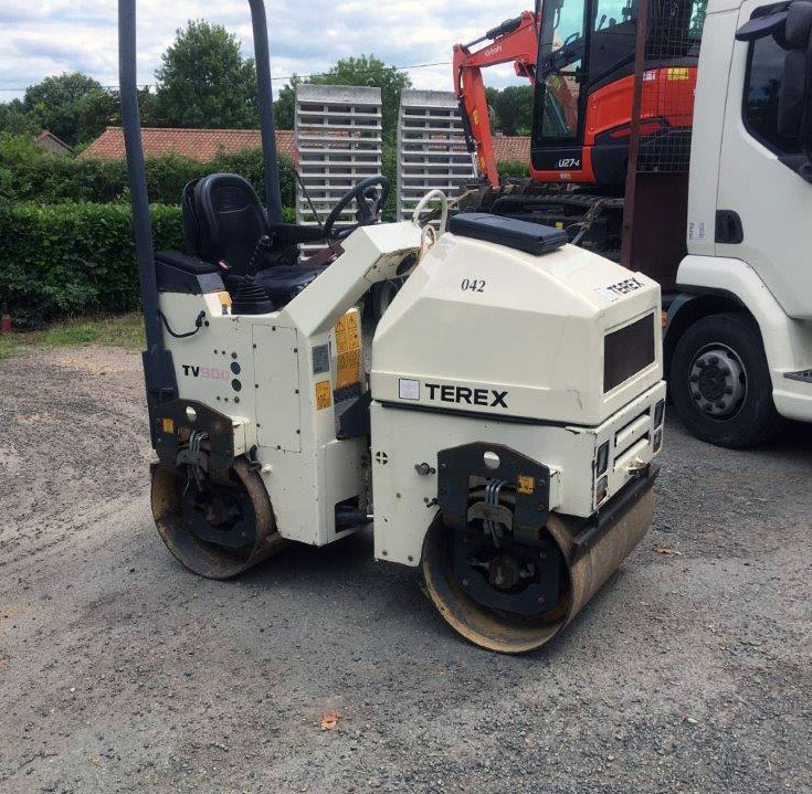 white vibrating roller machine with lorry and digger in the background